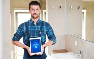 Technician of home service company holding touchpad with homepage on display